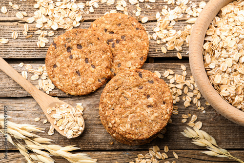 Delicious oatmeal cookies, oat flakes and spikes on wooden table, flat lay
