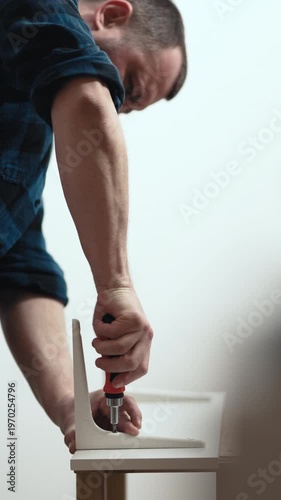 Close up of man screwing bolt into wall shelf with manual screwdriver, DIY home repair, 4K.