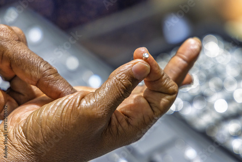 A close-up view of a person's hands delicately holding and examining a small, sparkling gemstone or diamond. Sri Lanka island in Asia.