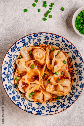 Wontons are placed in a bowl with spicy sauce.