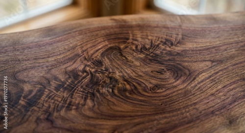A detailed macro perspective of the swirling, figured burl and intricate grain patterns within a polished, live-edge walnut slab.