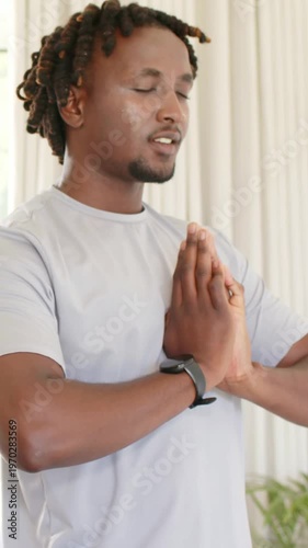 Vertical video: Bringing hands together man meditating at home, holding prayer pose with wristwatch