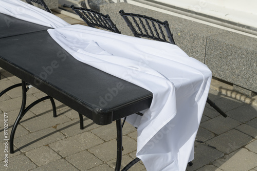 black table and white table cloth with fancy chairs outside