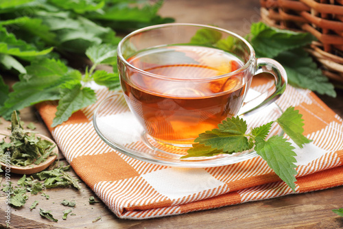 Nettle leaf tea with fresh green leaves on wooden rustic table, closeup, copy space, natural medicine, diet food and drink, homeoparhy, hair and skin healthy care, detox and diet healthy food concept