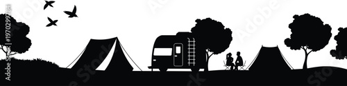 Silhouette of a couple sitting outside their camper van between two tents in a nature landscape with trees and flying birds for outdoor camping concept.