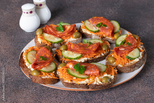 Quadro su tela Sandwiches with carrots, chorizo, cucumber and green olives on white plate