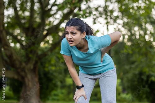Woman experiencing lower back pain during outdoor exercise