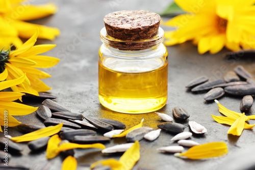 Sunflower oil with fresh flowers, seeds, petals on black table, closeup, copy space, cooking ingredient, face skin and hair care, natural organic food concept