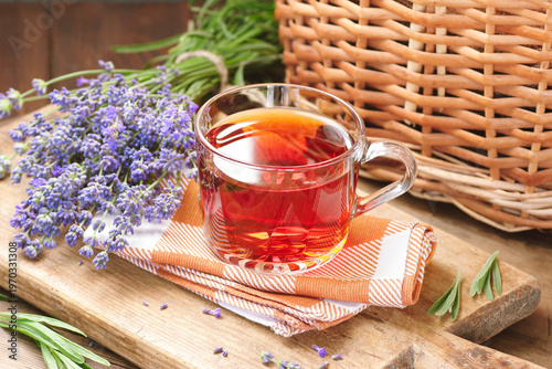 Lavender herbal tea in a glass cup with flowers on wooden rustic background, closeup, sleep and skin healing drink, natural medicine and naturopathy concept