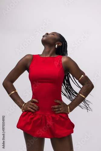 Portrait of joyful African American young woman wearing red dress and posing over white background. Isolated.