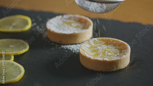 Wallpaper Mural Baker dusts lemon tarts with powdered sugar on a black slate, garnished with fresh lemon slices. Torontodigital.ca