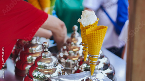 Vendor serving refreshing gelato scoops in waffle cones at an outdoor market stall