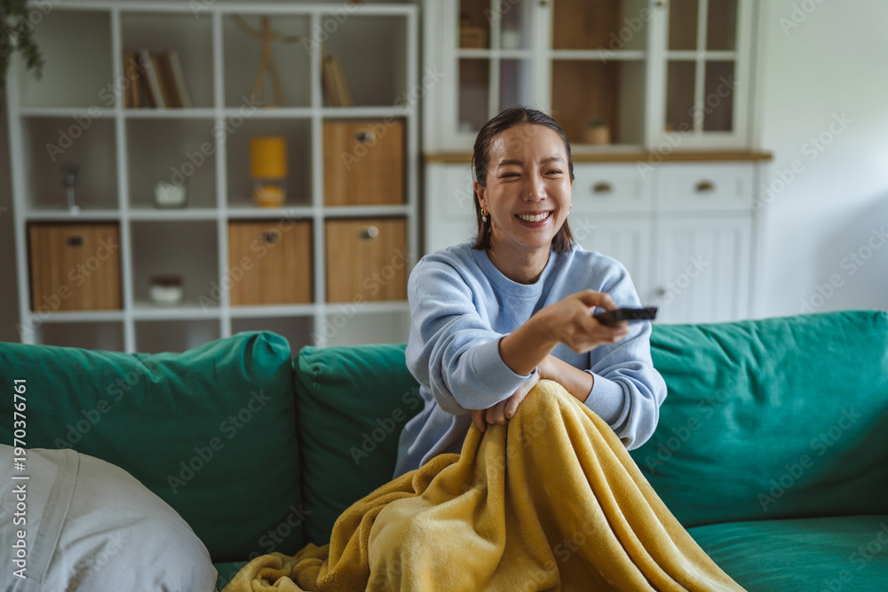 Obraz premium Woman relaxing at home watching television with remote control