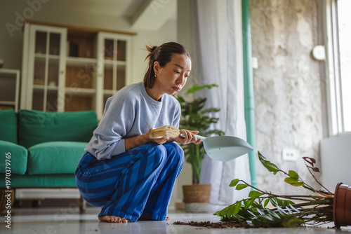 Foto Woman cleaning up fallen houseplant and spilled soil