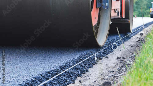 Obraz na plátně Road roller compacting fresh asphalt on a new road construction site