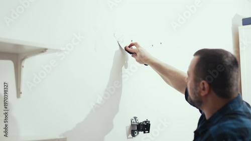 Handyman filling holes on white wall with putty knife, wall preparation process, high quality 10 bit 4K.