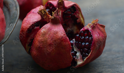 Close-up of a cracked ripe pomegranate with juicy red seeds.