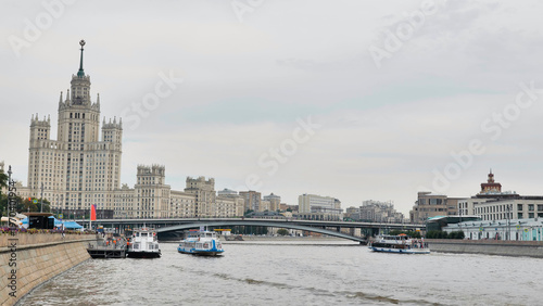 Canvas Print Moscow city skyline with Stalinist skyscraper and river traffic under a cloudy s