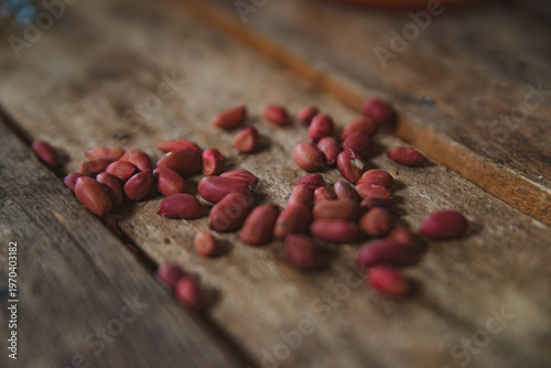 Fotografija Close-up of a pile of red-skinned peanuts scattered on a rough wooden surface, creating a sense of simplicity and naturalness