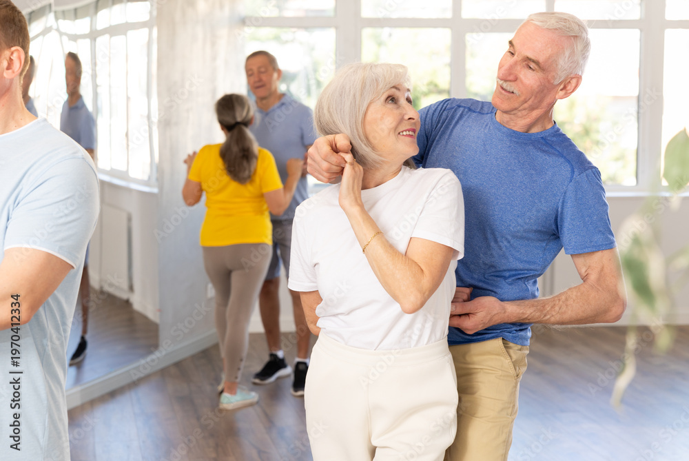 Fototapeta premium Smiling elderly woman with male partner in latin dance class. Social dancing concept