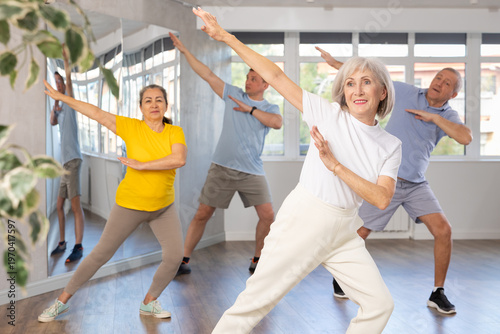 Elderly woman dances energetic modern dances in group in studio