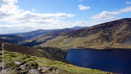 Foto Mountain lake valley landscape with rolling hills and blue sky