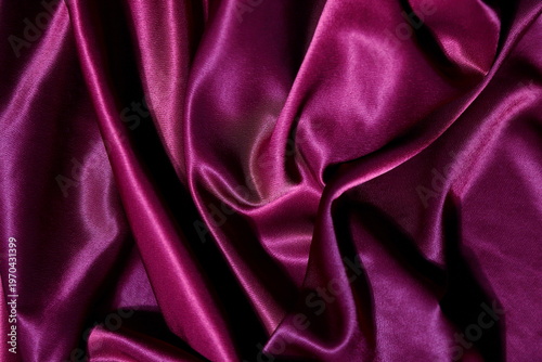 Luxurious deep magenta satin fabric with elegant folds and soft light reflections
