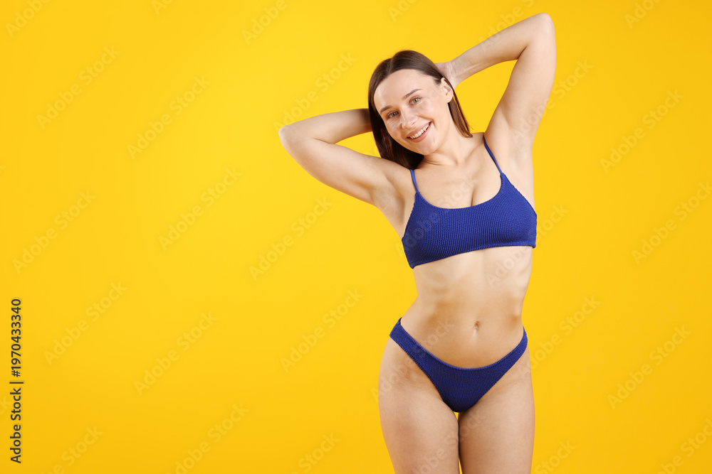 Fototapeta premium Beautiful woman wearing stylish swimsuit on yellow background. Space for text