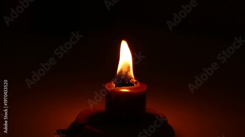 Closeup candle beautiful burning on dark shadow red warm background, candle fire flame light with empty copy space. Magic ritual with romantic candle wax fire