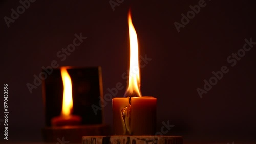 Bright active burning candle on dark shadow red warm background near the mirror, candle fire flame light with copy space. Magic ritual with romantic candle wax fire