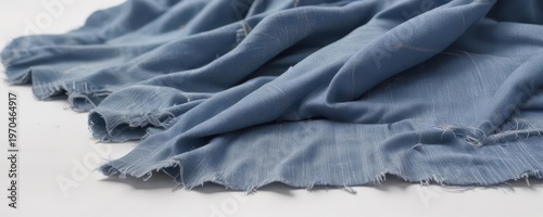 A snippet of faded denim fabric is scattered on a clean white surface, revealing worn denim fibers and thread texture ,  thread snag, faded denim