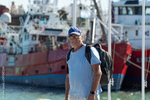 Medio cuerpo hombre mayor relajado y contento con paisaje naval de fondo con desenfoque