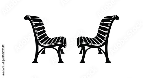 Two ornate park benches face each other in a stark silhouette