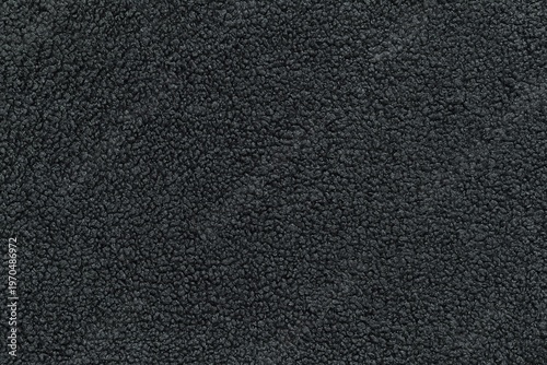 Detailed texture of dark grey sherpa fleece fabric. Top view close-up of soft curly textile material for outerwear and interior design