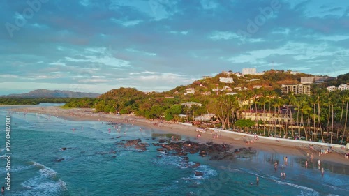 Aerial landscape view of the town of Tamarindo in Costa Rica with Pacific Ocean, waves, coastline, tourists, homes and hotels climbing up the hills of the town
