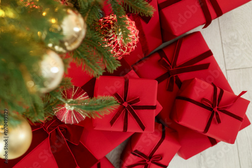 Many gift boxes under Christmas tree indoors, top view
