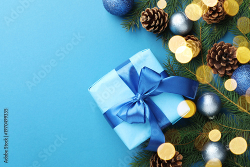 Merry Christmas and Happy New Year. Festive composition with gift and decor on light blue background, flat lay. Space for text