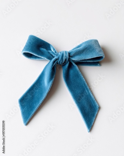 A single blue velvet ribbon tied in a simple bow on a white surface