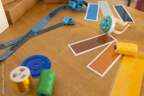 Planning sparking swatches fanning tape coiling pincushion holding pins spools lying on wood table