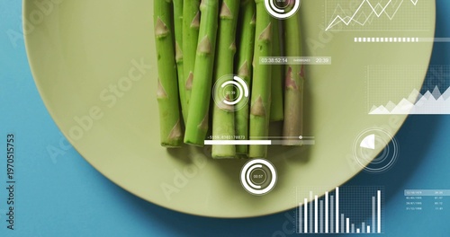 Displaying bundle of green asparagus aligned on yellow plate on cyan-blue studio tabletop, with HUD