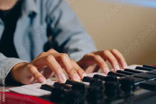 Canvas Print Person playing keyboard piano with focused hands on keys, creating music indoors