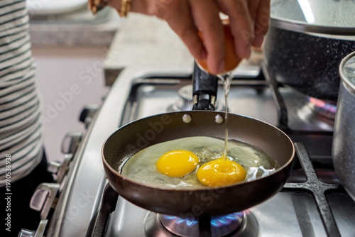 Konstfotografi Hands cracking eggs in frying pan for breakfast
