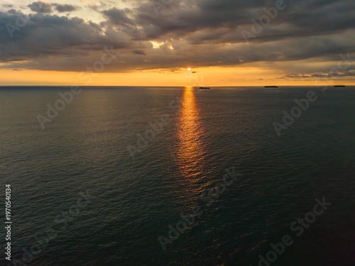 Golden sunlight dances on serene waters at sunset over the horizon, creating a tranquil atmosphere