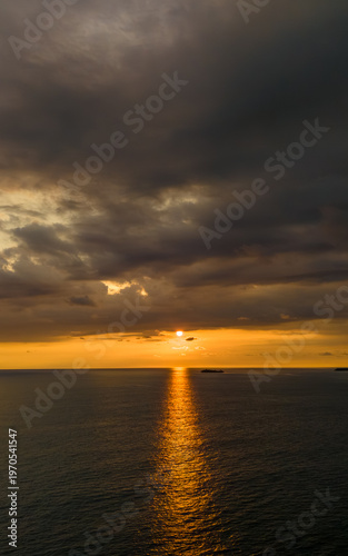 Stunning sunset over tranquil ocean waters with golden reflections and dramatic clouds on a serene evening