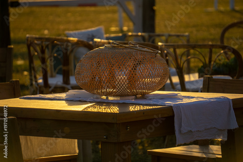 Vintage wooden crate with green foliage next to a rustic lantern on a wooden surface.