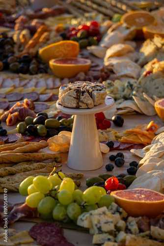 Lavish charcuterie board and grazing table with cheeses, fruits, and cold cuts.