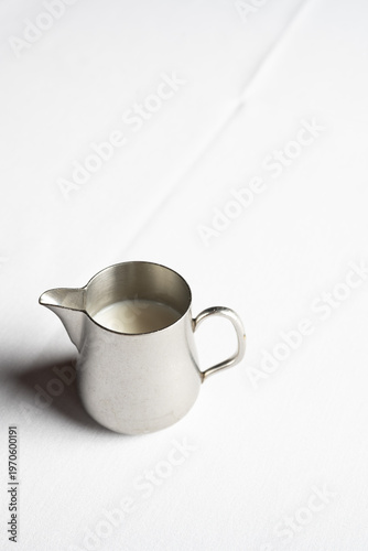 Silver Pitcher of Milk on White Table