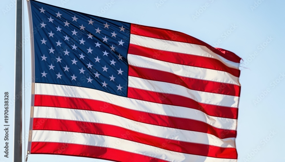 Fototapeta premium Symbol of Freedom: A vibrant American flag waves proudly against a clear sky, embodying the essence of liberty and national pride.