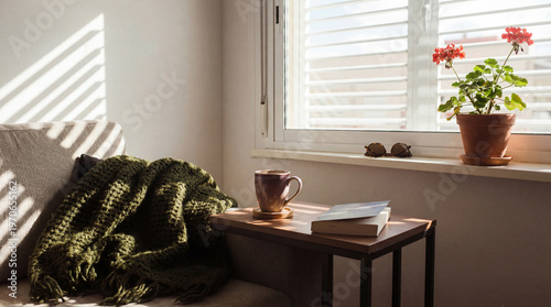 Foto Tranquil sun-drenched living room corner with a cozy sofa, green blanket, books, and potted geranium on windowsill