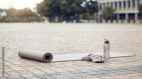 Φωτογραφία An outdoor fitness setup featuring a yoga mat, water bottle, towel, and sunglasses
